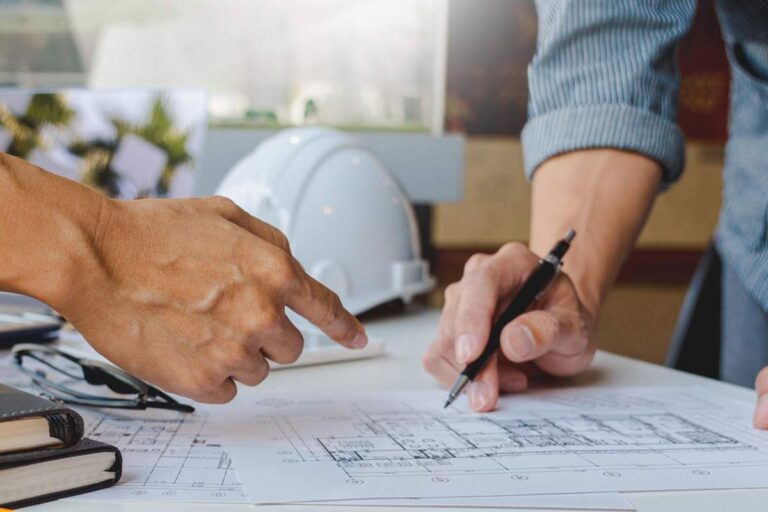 Homeowner reviewing a contractor license card, insurance certificate, and written construction contract at a kitchen table.